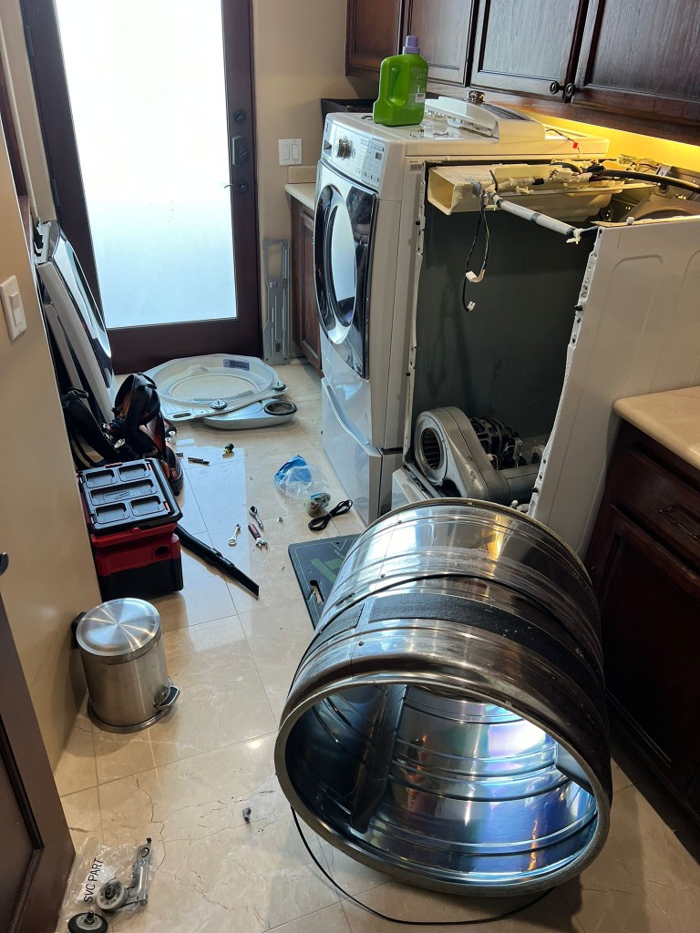Professional dryer repair technician replacing heating element in front load dryer