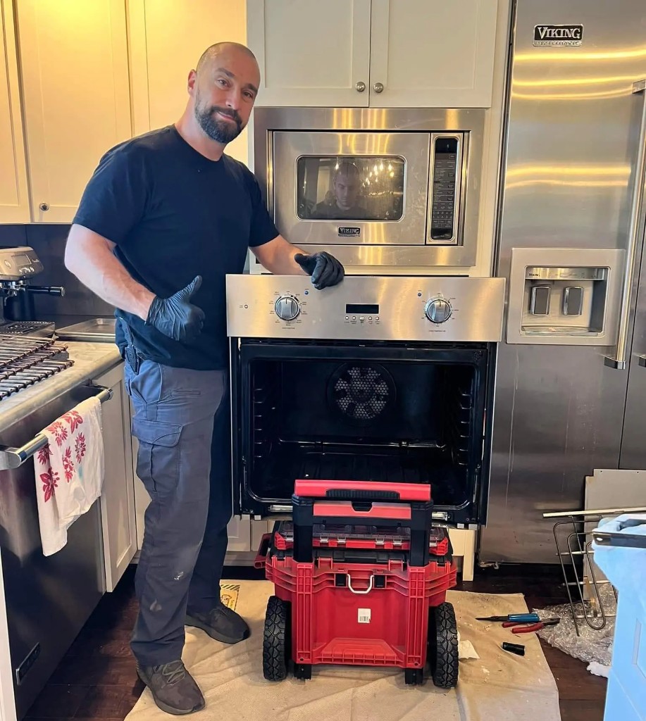 Professional oven and stove repair technician fixing electric oven heating element in modern kitchen